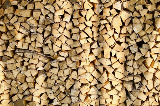 Heap of chopped firewood in pile close-up. Firewood storage close up. Stock of wooden logs. Chopped wood in bright sunlight. Rustic lifestyle. Woodpile with firewood full frame image. Wooden texture.