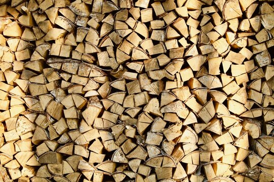 Heap of chopped firewood in pile close-up. Firewood storage close up. Stock of wooden logs. Chopped wood in bright sunlight. Rustic lifestyle. Woodpile with firewood full frame image. Wooden texture.