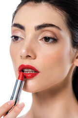 brunette young woman applying red lipstick isolated on white