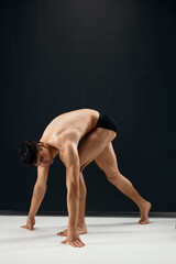 Fototapeta na wymiar bodybuilder with muscular body in black shorts posing dark background