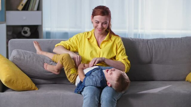 relationship with children, loving woman having fun with little laughing boy on the sofa while relaxing at home together