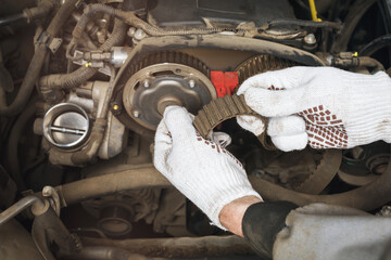 An auto mechanic checks the condition of an old timing belt for various defects, close-up - obrazy, fototapety, plakaty