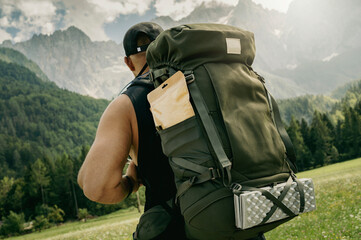 Strong Man with big backpack going on a hike, Alpine mountains in background