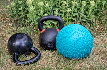 rubber slam ball filled with sand and iron kettlebells in a backyard, home gym, exercise and...