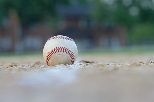 Long telephoto image of a well worn baseball sitting on the foul line leading to first base