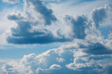 Blue sky background with fluffy white clouds. Vivid view of natural scene at sunny day