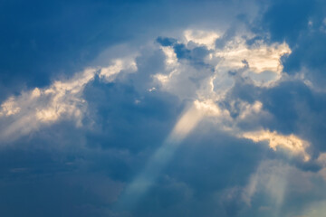 Sun shining through thick evening clouds. Bright view of natural colorful background.
