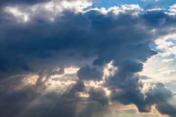 Evening sun rays through thick clouds. Bright view of natural colorful background at sunset.