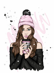 Beautiful girl in a hat with a bubo and with a glass of coffee or tea. Woman with long hair in stylish clothes. Fashion and style, accessories. Autumn, winter, warm drink. Hipster. - 451677421