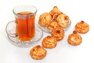 homemade flavored coconut cookies and a cup of hot tea on white glossy surface
