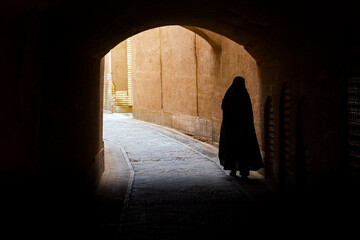 A woman with a hijab walking in a street of Yazd in Iran