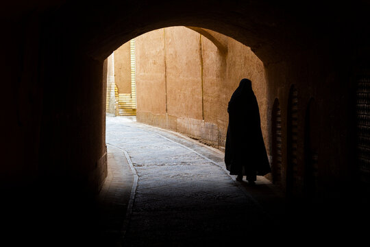 A woman with a hijab walking in a street of Yazd in Iran