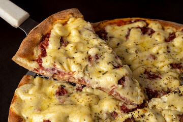 Piece of pizza with mozzarella cheese and dried meat