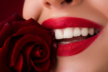 Lips with lipstick closeup. Beautiful woman lips with smile. Close-up beautiful female lips with bright red makeup. Perfect clean skin, sexy lip make-up. Beautiful spa portrait with tender red rose