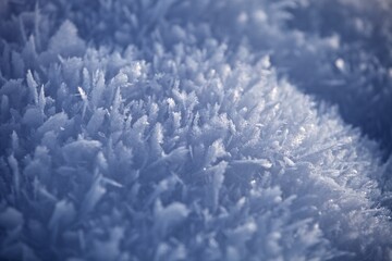 White ice crystals in bright sunlight. Macro photography of ice crystal texture. Snow crystals close-up on a bright frosty winter day. White sparkling snow surface close up. Abstract snowy pattern.
