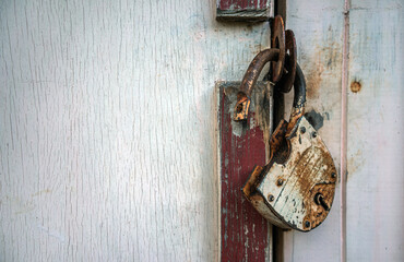 An old rusty padlock on the door of a pink wooden shed. Closed doors. Breaking locks.