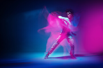 Fototapeta na wymiar Dancing mixed race girl in colourful neon studio light. Female dancer show expressive hip hop dance. Long exposure