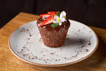 Tasty chocolate cupcake with strawberry on wooden table