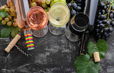 White wine rose red wine in glasses choice for tasting. Types of wine in bottles. Different varieties grapes. Wine composition with on dark moody stone background. Mediterranean drinks bar degustation