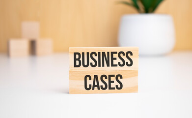 On a light background, wooden cubes and a wooden block with the text business cases. View from above