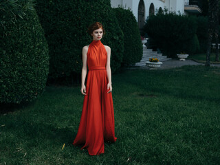 pretty woman in red dress elegant style green bushes in the garden