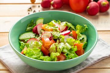 Recipe for vegetable salad with tomatoes, cucumbers and radishes. Seasonal dish on wooden background. Vegan food for diet.