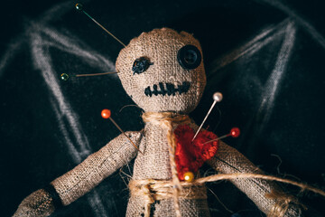 Voodoo rag doll with buttons instead of eyes and studded with needles, close-up top view.