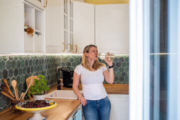 beautiful blonde woman drinking fresh water in her modern kitchen