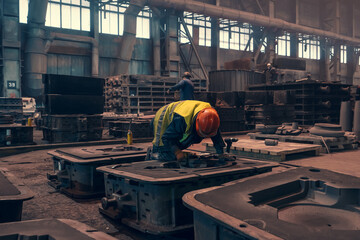 Worker with molds for metal cast in metallurgical plant foundry. Heavy industry.