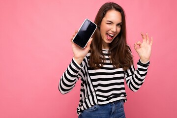 Photo of winking beautiful happy young woman wearing striped sweater isolated over background with...