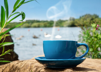 blue cup of coffee on the lake shore 