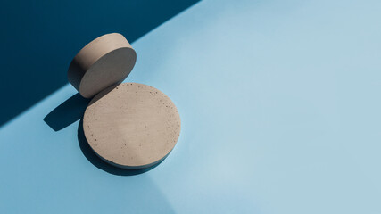 Concrete round podium in sun light with shadow on blue background. A scene with cement display show case for cosmetic beauty brands products mock up. Minimalistic abstract shopping sales concept