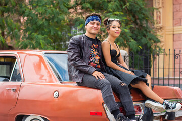 Young couple sitting on a car on the street
