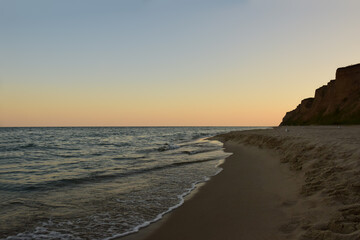 Fototapeta premium Morning sea sandy beach, with rocks and several distant seagulls