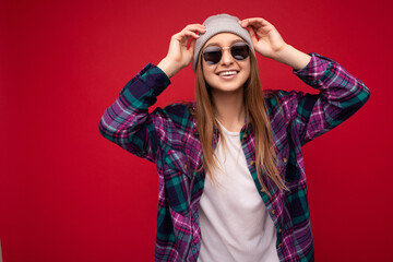Photo shot of beautiful positive young brunette woman wearing summer casual clothes and stylish sunglasses isolated over colorful background wall looking at camera