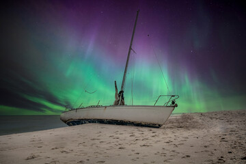 Aurora borealis over a shipwreck off the coast of Uttakleiv Beach