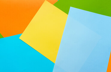 A five sheets of colored paper (blue, turquoise, yellow, green, orange) are mixed. Design cardboard background, copy space.