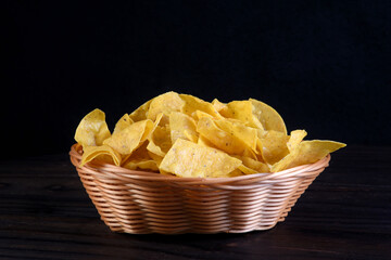 delicious mexican corn nachos inside reed canister isolated on black background.