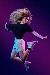 Latin dancer jumping with flying chinese hair and urban outfit, with blue and purple background