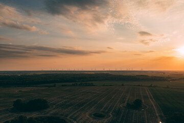 Drone photography of the wind turbine farm on the green fields of Poland during late early summer. Sustainable energy generation from the wind turbines.