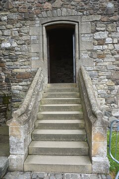 Steps leading up to a dark doorway in the exterior wall of an ancient stone building