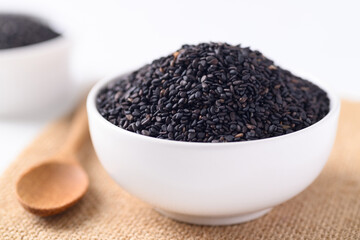 Black sesame seeds in a white bowl with wooden spoon, Food ingredients