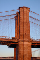 One of the towers of the famous old and historic Brooklyn Bridge spanning the East River from Manhattan into Brooklyn as seen at sunset