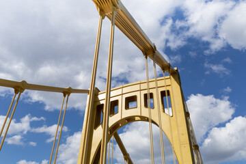 Bright sunlight on the upright structure of a yellow self anchored suspension bridge, deep blue sky...