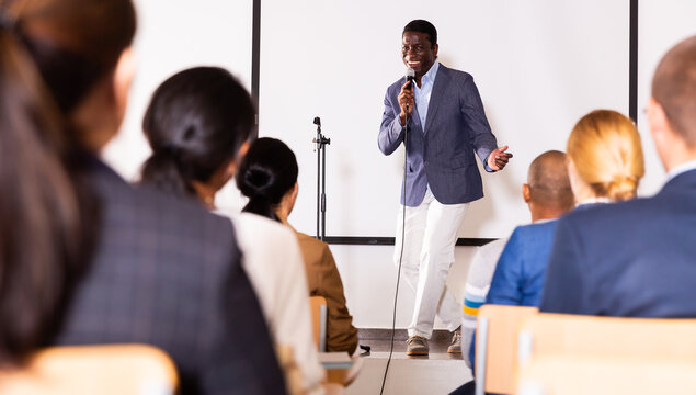 Excited African American Preacher Giving Motivational Speech To Business People From Stage In Conference Hall