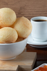 Brazilian snack cheese bread (pão de queijo) in white bowl and coffee.