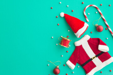 Flat lay of Christmas composition, Christmas ornament, santa claus dress on green background copy space minimal style. Christmas ornament for decoration in xmas new year winter festival.