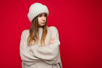 Photo shot of beautiful offended resentful young dark blonde woman standing isolated over red...