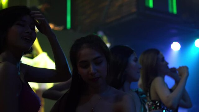 Group of Confidence Asian woman dancing to dj club music with illuminated neon night lights at night club. Fashionable female friends enjoy and having fun nightlife dance party together at nightclub.