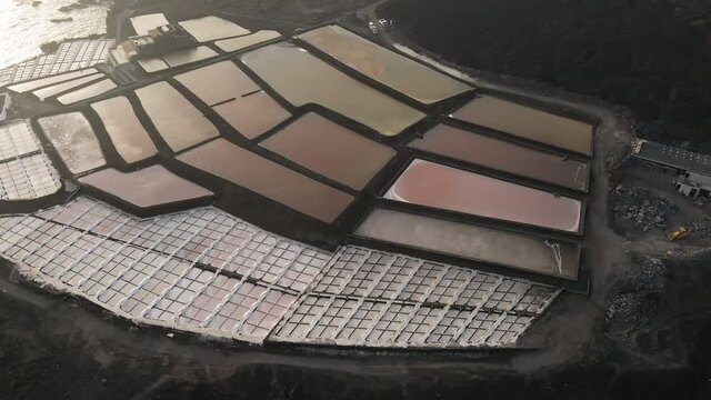 Vivid hues of salt-extraction complex; golden hour, aerial dolly out